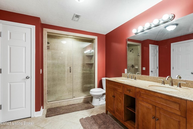 bathroom featuring tile patterned floors, a stall shower, toilet, and a sink