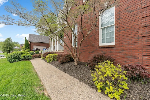 view of side of property featuring brick siding and a lawn