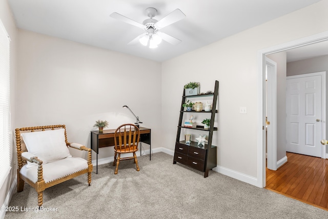 living area with a ceiling fan, light colored carpet, and baseboards