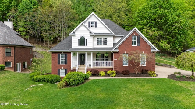 view of front of house with a front yard, roof with shingles, covered porch, and brick siding
