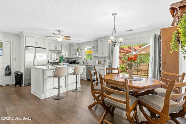 dining area with dark wood-style floors, a textured ceiling, visible vents, and ceiling fan