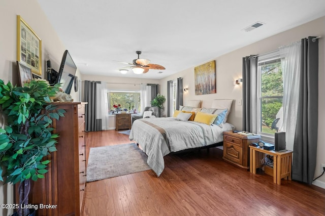 bedroom featuring visible vents, wood finished floors, a ceiling fan, and multiple windows