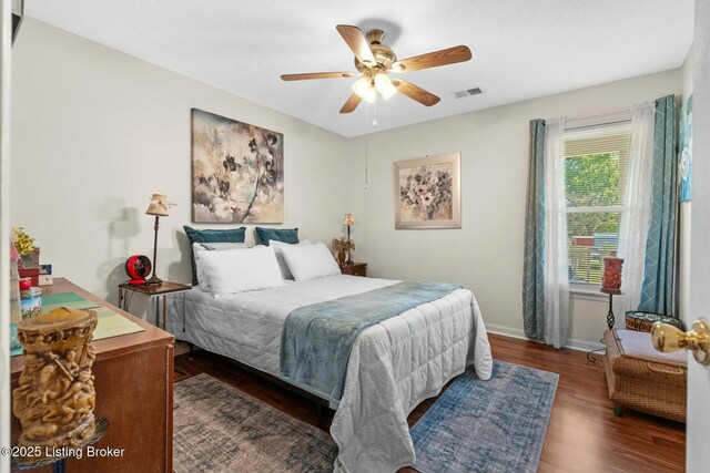 bedroom featuring a ceiling fan, visible vents, wood finished floors, and baseboards