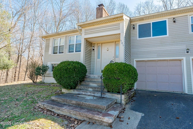 view of front of home featuring a chimney, an attached garage, and driveway
