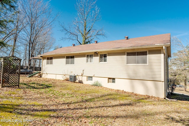 back of property with a lawn and central AC
