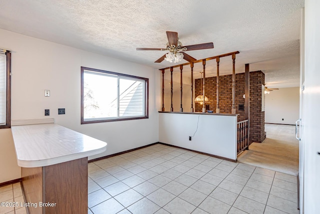 interior space with light tile patterned flooring, a textured ceiling, a ceiling fan, and baseboards