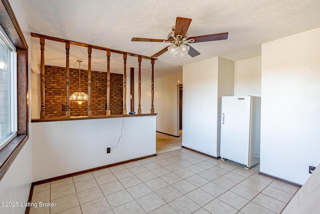 empty room featuring a ceiling fan, baseboards, a textured ceiling, and light tile patterned floors