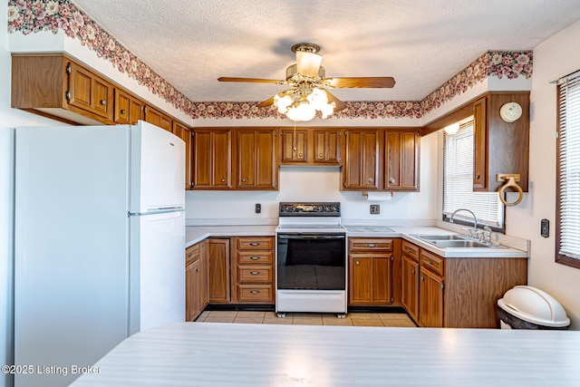 kitchen with a sink, freestanding refrigerator, a ceiling fan, light countertops, and electric stove