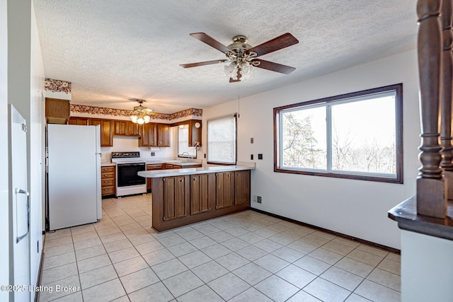 kitchen with a ceiling fan, a sink, white appliances, a peninsula, and a textured ceiling
