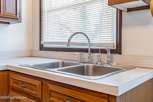 kitchen with light countertops, a sink, and brown cabinets