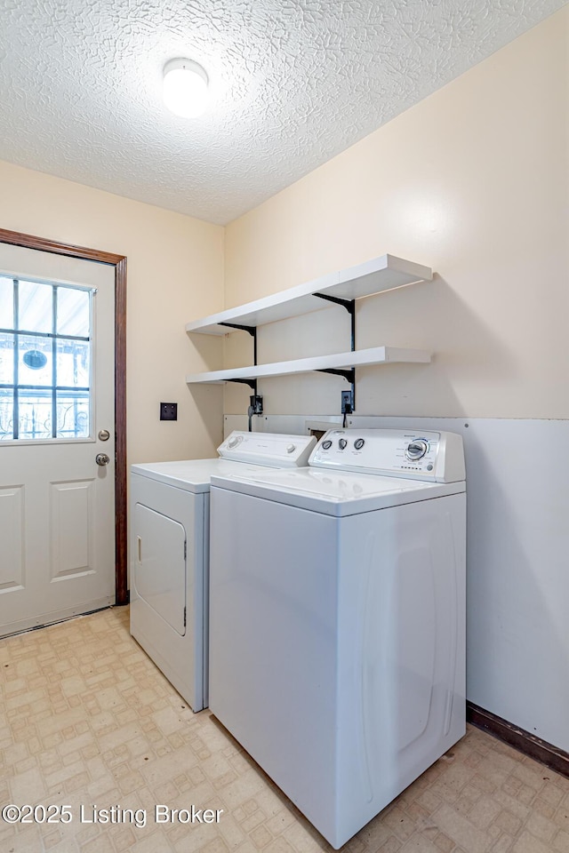 clothes washing area with a textured ceiling, baseboards, independent washer and dryer, light floors, and laundry area