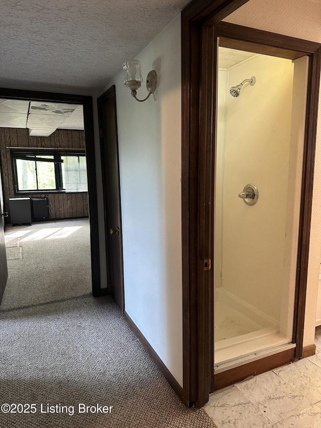 corridor featuring carpet floors, a textured ceiling, and baseboards