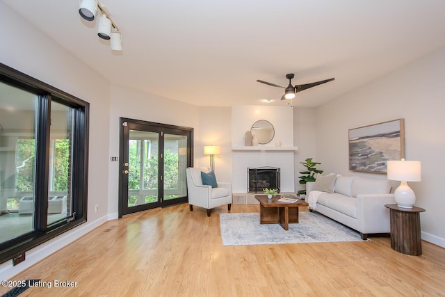 1038 Garden Creek Cir, Louisville, KY 40223 - living area with light wood-type flooring, baseboards, a fireplace with raised hearth, and a ceiling fan