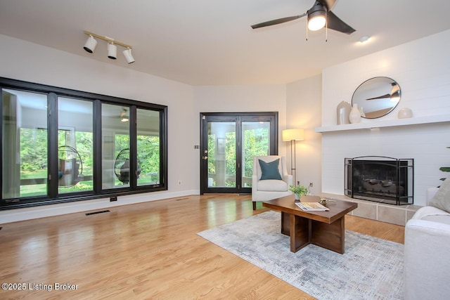 1038 Garden Creek Cir, Louisville, KY 40223 - living room with a tile fireplace, a ceiling fan, and light wood-type flooring