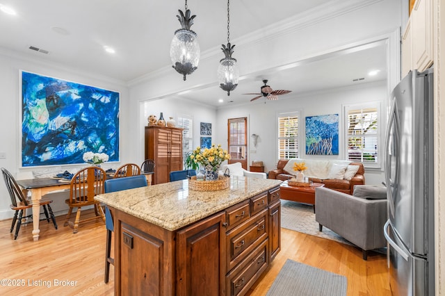kitchen featuring visible vents, light wood-type flooring, light stone counters, freestanding refrigerator, and open floor plan