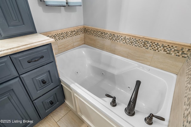 full bathroom featuring a tub with jets, tile patterned floors, and vanity
