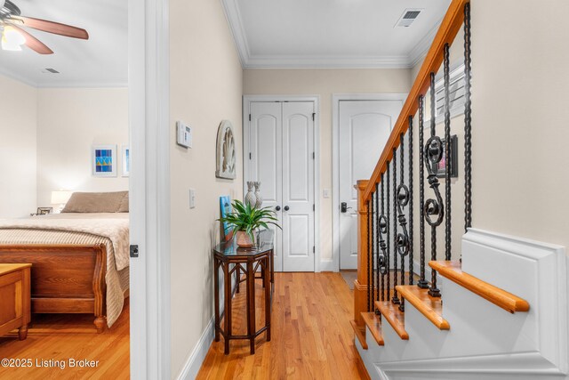 foyer entrance featuring crown molding, visible vents, light wood-style floors, baseboards, and ceiling fan
