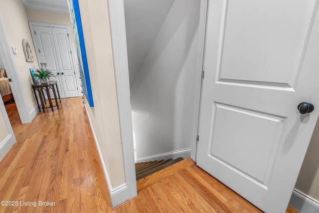 hallway with crown molding, baseboards, and light wood finished floors