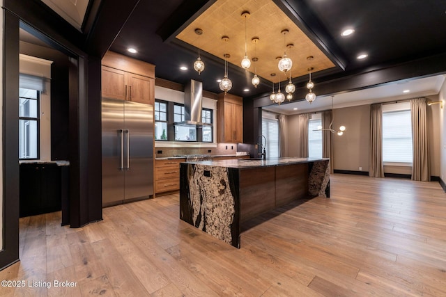 11004 Meeting St, Prospect, KY 40059 - kitchen with built in refrigerator, range hood, stone counters, light wood finished floors, and an island with sink