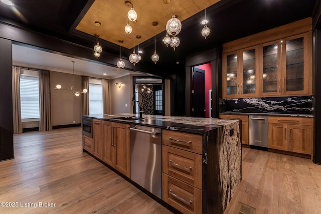 11004 Meeting St, Prospect, KY 40059 - kitchen with appliances with stainless steel finishes, a sink, brown cabinets, light wood-type flooring, and a center island with sink