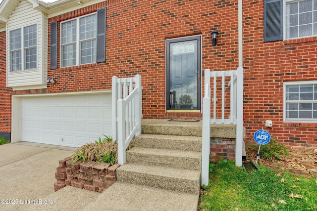 entrance to property featuring brick siding, driveway, and an attached garage