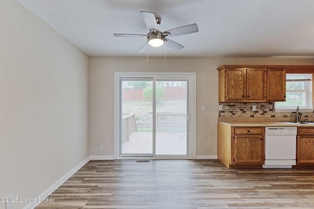 kitchen featuring a sink, light wood-style floors, light countertops, dishwasher, and a ceiling fan