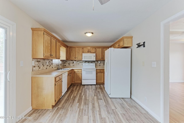 kitchen featuring light countertops, white appliances, light wood-type flooring, and a sink