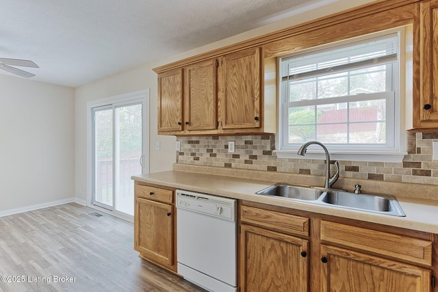 kitchen with tasteful backsplash, plenty of natural light, dishwasher, and a sink