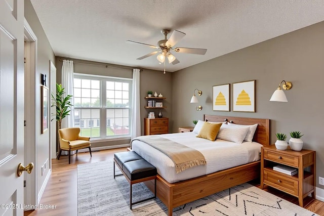 bedroom with a textured ceiling, baseboards, and light wood-type flooring