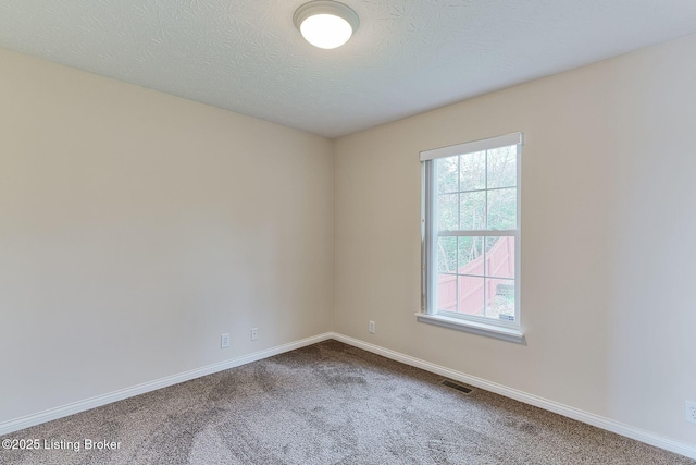 unfurnished room with a textured ceiling, visible vents, carpet floors, and baseboards