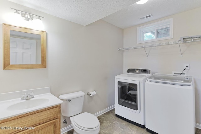 bathroom with independent washer and dryer, visible vents, baseboards, toilet, and vanity