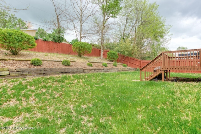 view of yard with a deck, stairs, and fence