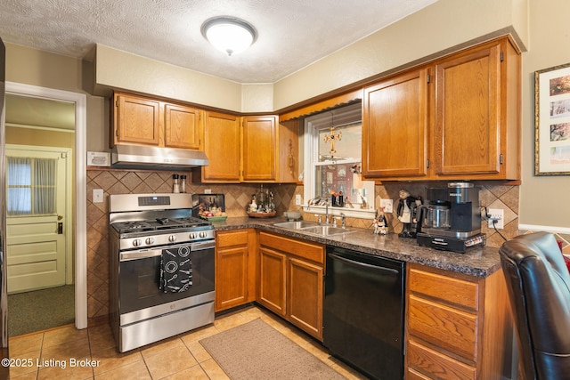 kitchen featuring tasteful backsplash, stainless steel gas range oven, under cabinet range hood, dishwasher, and a sink