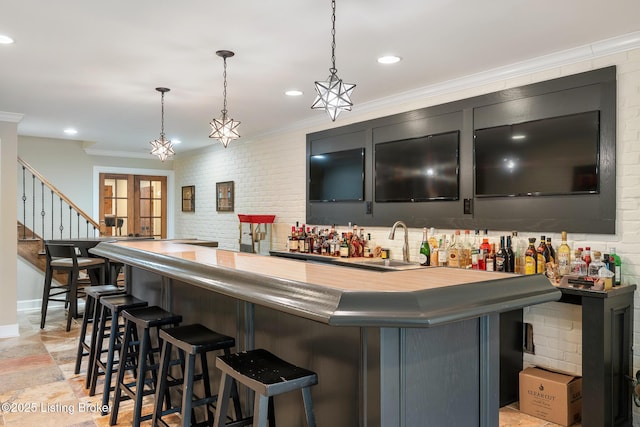 bar with decorative light fixtures, crown molding, wet bar, and a sink