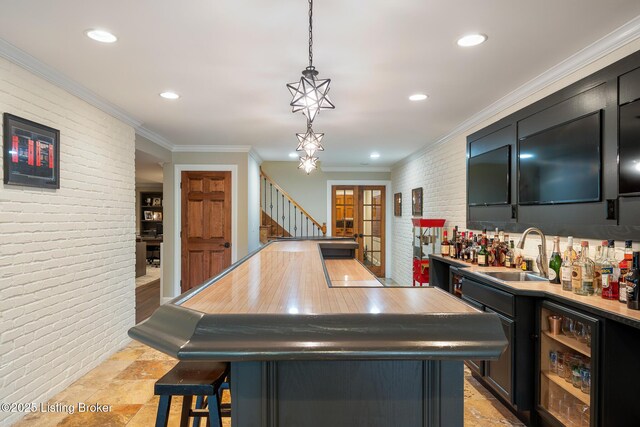 bar featuring brick wall, indoor wet bar, a sink, stairway, and pendant lighting