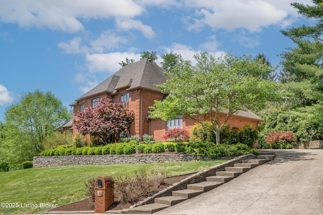 view of home's exterior featuring a yard, a shingled roof, and brick siding