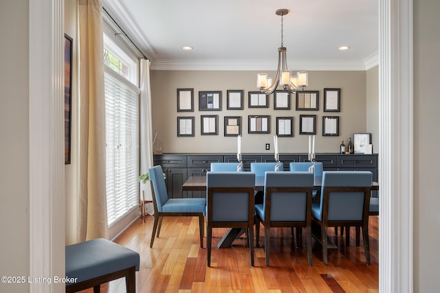 dining area featuring an inviting chandelier, ornamental molding, and light wood-style flooring