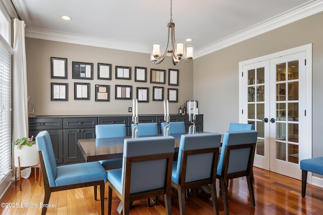 dining area featuring wood-type flooring, an inviting chandelier, recessed lighting, ornamental molding, and french doors