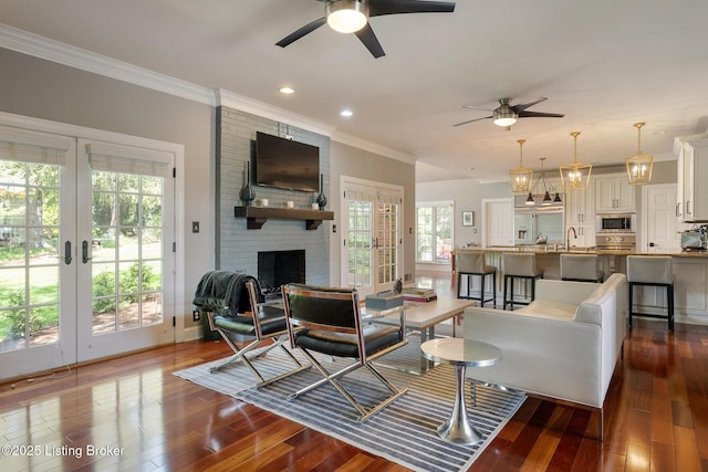 living area with dark wood-type flooring, ceiling fan, and ornamental molding