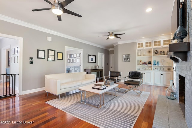 living room featuring baseboards, light wood-type flooring, ornamental molding, and a ceiling fan