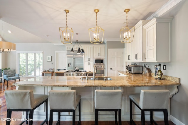 kitchen featuring a peninsula, decorative light fixtures, light stone counters, and built in appliances