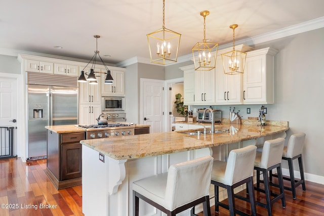 kitchen featuring built in appliances, a peninsula, a kitchen island, and dark wood-type flooring