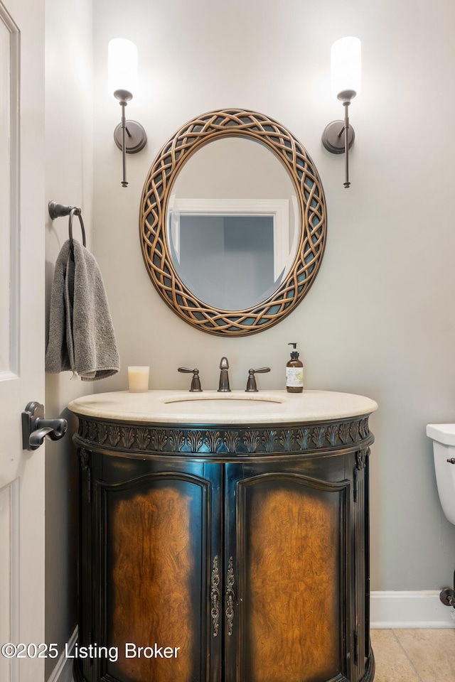 bathroom with toilet, vanity, and baseboards