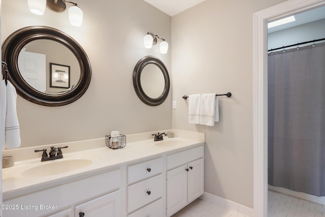 full bathroom featuring tile patterned floors, baseboards, double vanity, and a sink