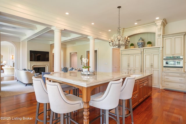kitchen featuring oven, a spacious island, light stone counters, a kitchen breakfast bar, and dark wood-style floors