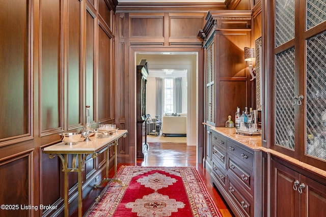 bathroom with a decorative wall, ornamental molding, and wood finished floors