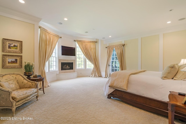 carpeted bedroom featuring ornamental molding, recessed lighting, a fireplace with raised hearth, and access to exterior