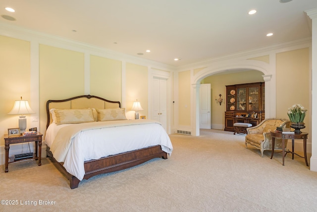 bedroom with light colored carpet, ornamental molding, arched walkways, and recessed lighting