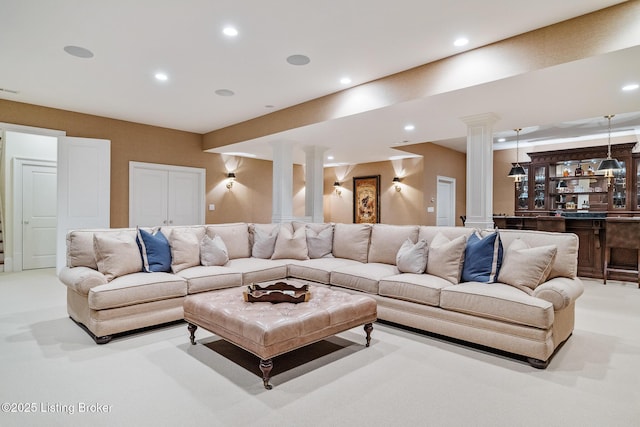 living area with ornate columns, recessed lighting, and bar