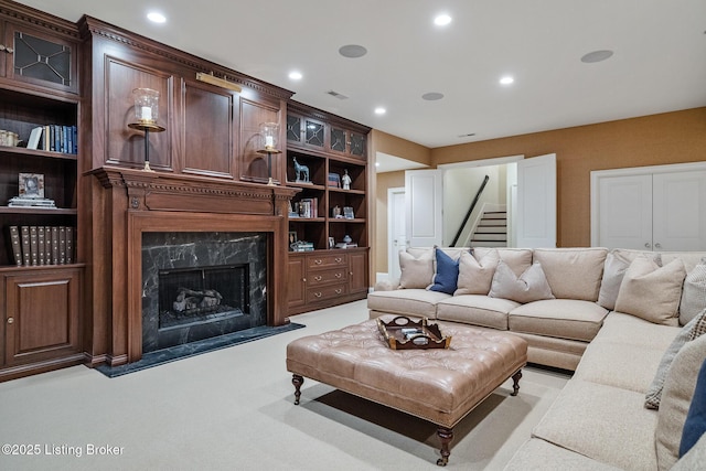 living area with a high end fireplace, recessed lighting, stairs, and light colored carpet